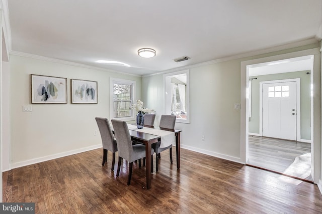 dining room featuring baseboards, visible vents, wood finished floors, and ornamental molding