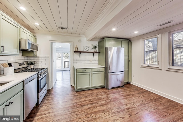 kitchen with stainless steel appliances, visible vents, green cabinets, light countertops, and tasteful backsplash