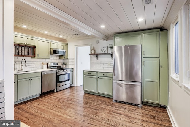 kitchen with stainless steel appliances, a sink, green cabinets, light countertops, and open shelves