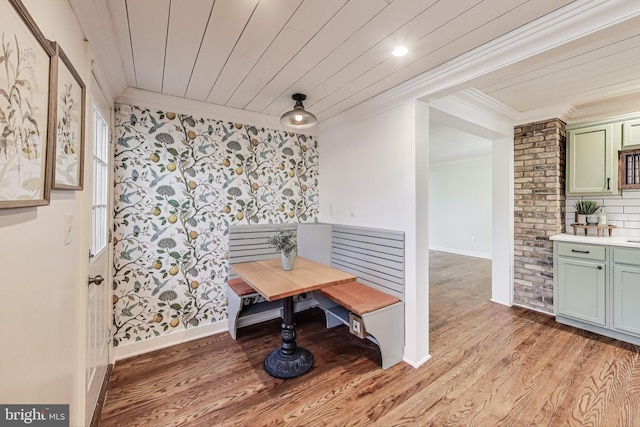 dining area featuring light wood-type flooring, wooden ceiling, baseboards, and ornamental molding