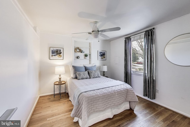 bedroom with ceiling fan, baseboards, and wood finished floors