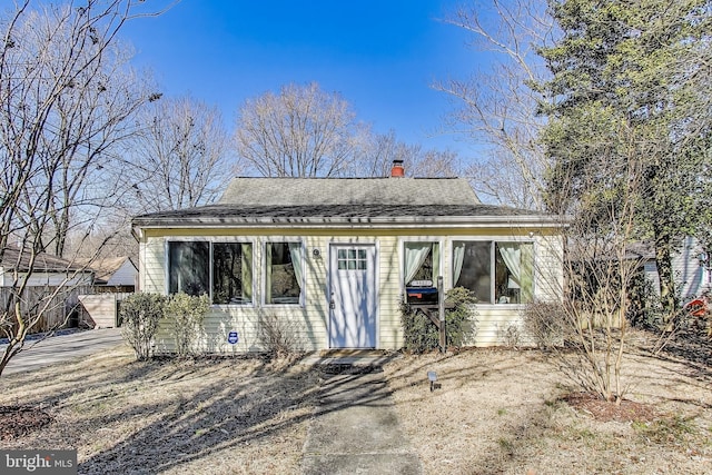 rear view of property featuring a chimney and roof with shingles