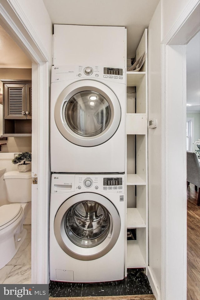 laundry room with marble finish floor, laundry area, and stacked washer and clothes dryer