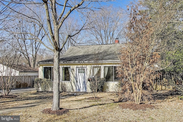 exterior space with a shingled roof, a chimney, and fence