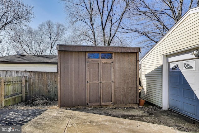 view of shed featuring a garage and fence