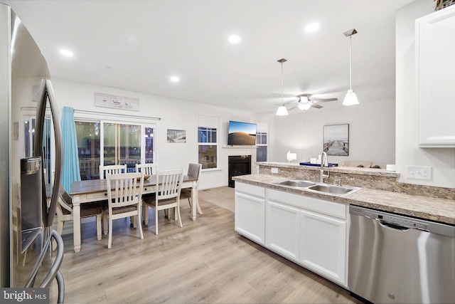 kitchen with appliances with stainless steel finishes, open floor plan, light countertops, pendant lighting, and a sink