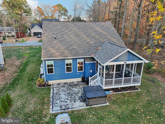 back of property featuring a sunroom, a hot tub, a yard, and roof with shingles