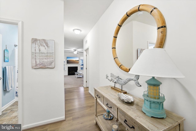 hallway featuring light wood finished floors and baseboards