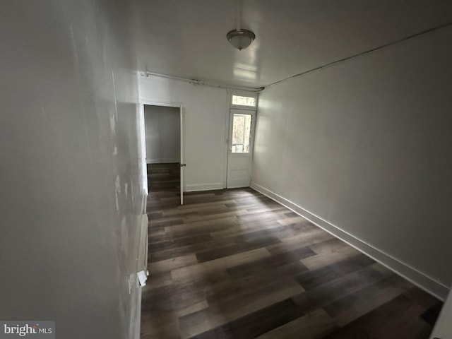 empty room with baseboards and dark wood-style flooring