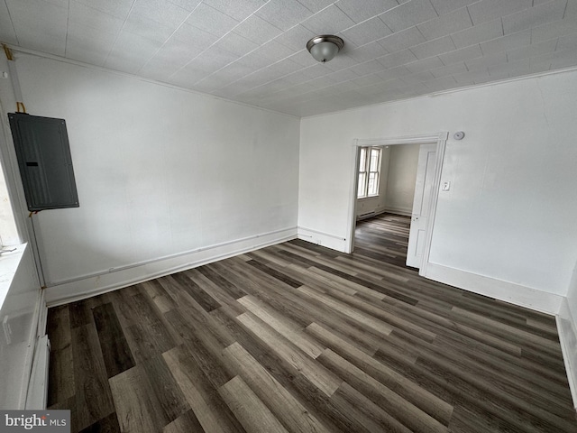 spare room with dark wood-style flooring, electric panel, and baseboards