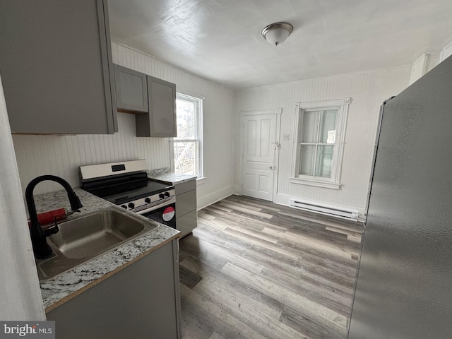 kitchen featuring a sink, stainless steel range with electric cooktop, baseboard heating, gray cabinets, and light wood finished floors