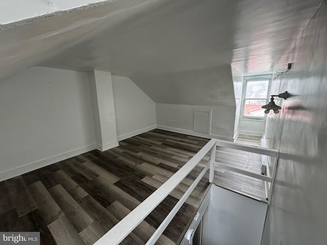 additional living space featuring lofted ceiling, dark wood-style flooring, and baseboards