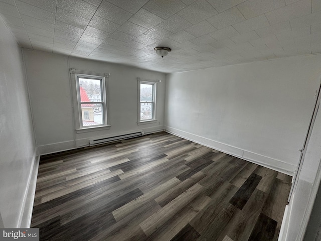 empty room featuring a baseboard radiator, baseboards, and dark wood-type flooring