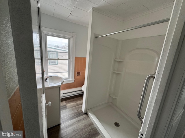 bathroom with a baseboard radiator, toilet, a stall shower, vanity, and wood finished floors