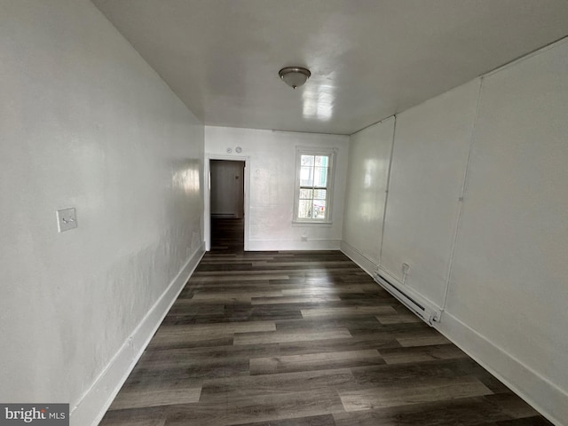 empty room with a baseboard radiator, dark wood finished floors, and baseboards