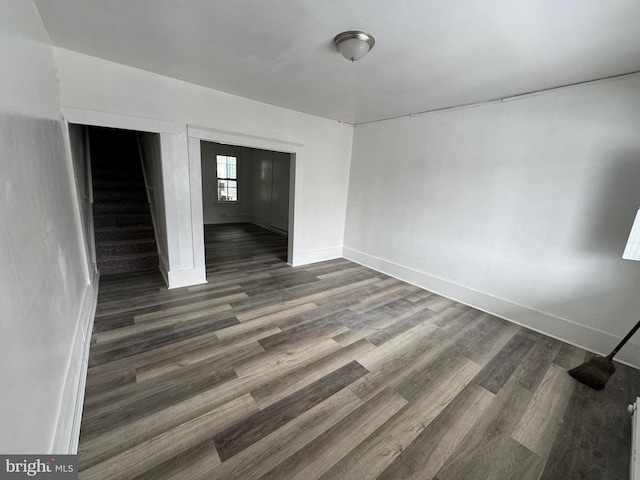 interior space featuring stairs, dark wood-type flooring, and baseboards