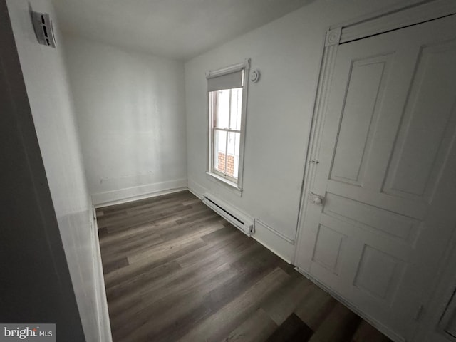 empty room featuring a baseboard heating unit, visible vents, baseboards, and dark wood-style floors