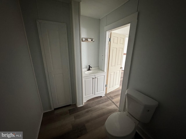 half bathroom with toilet, wood finished floors, and vanity