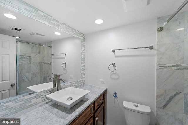 full bathroom with toilet, tiled shower, vanity, and visible vents