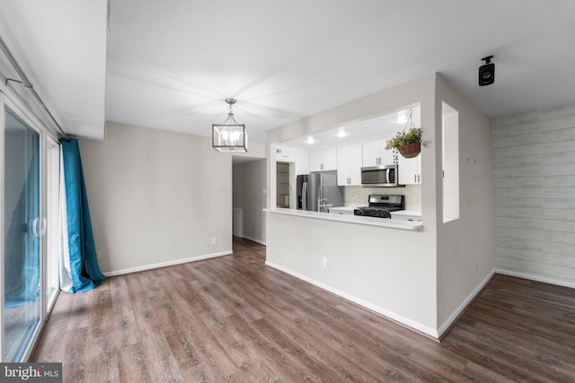 kitchen with white cabinets, dark wood finished floors, appliances with stainless steel finishes, a peninsula, and light countertops