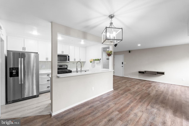 kitchen featuring light countertops, light wood-style flooring, appliances with stainless steel finishes, open floor plan, and white cabinetry