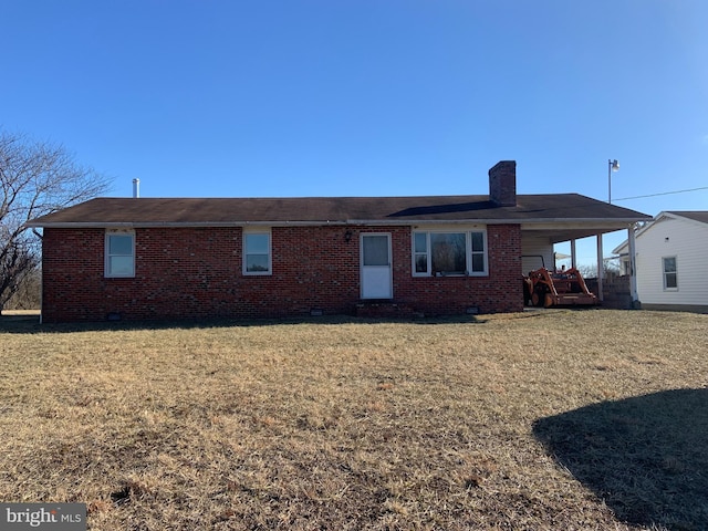 back of property with a yard, a carport, brick siding, and a chimney