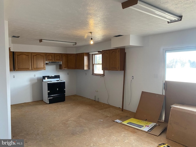 kitchen featuring visible vents, brown cabinetry, a textured ceiling, under cabinet range hood, and range with electric stovetop