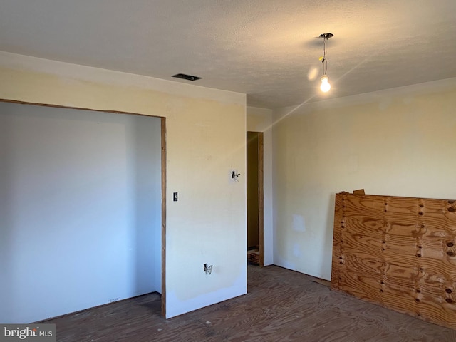 interior space featuring dark wood-type flooring, visible vents, and a textured ceiling