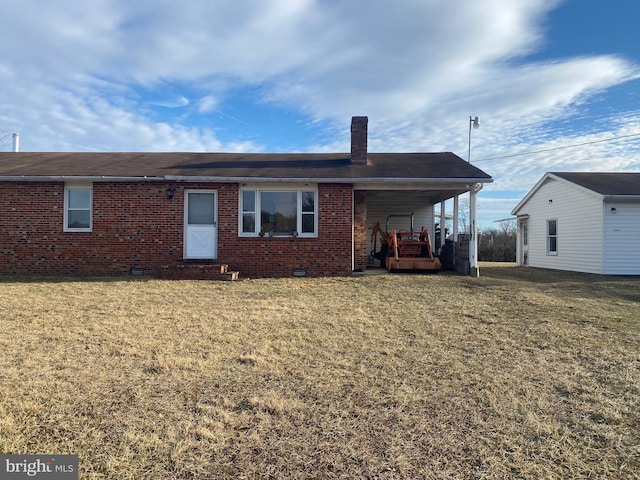 back of property featuring an attached carport, brick siding, a lawn, and a chimney