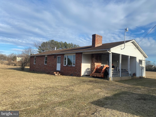 view of front facade with brick siding, a chimney, and a front yard