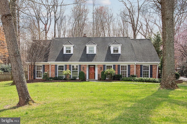 cape cod house featuring brick siding, roof with shingles, and a front yard