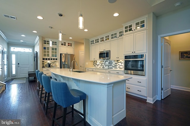 kitchen featuring a large island, decorative light fixtures, stainless steel appliances, light countertops, and white cabinetry