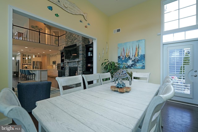 dining space featuring a fireplace, a towering ceiling, and visible vents