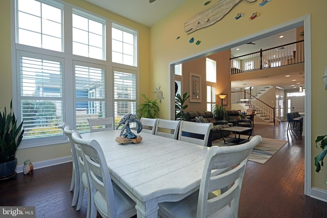 dining space with baseboards, a high ceiling, stairway, and dark wood-type flooring