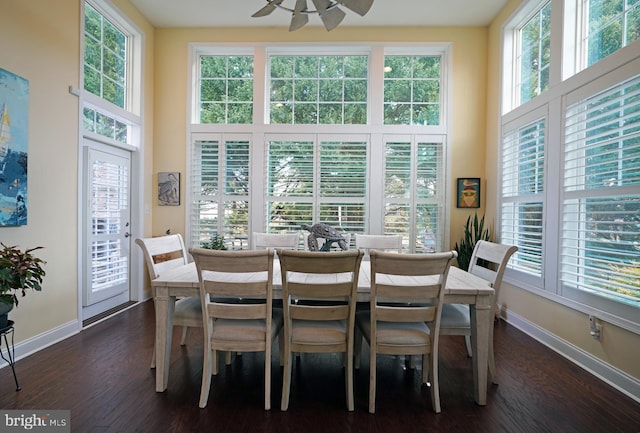 dining area featuring dark wood-type flooring, plenty of natural light, a high ceiling, and baseboards