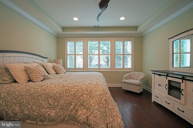 bedroom with dark wood-type flooring, a tray ceiling, and multiple windows