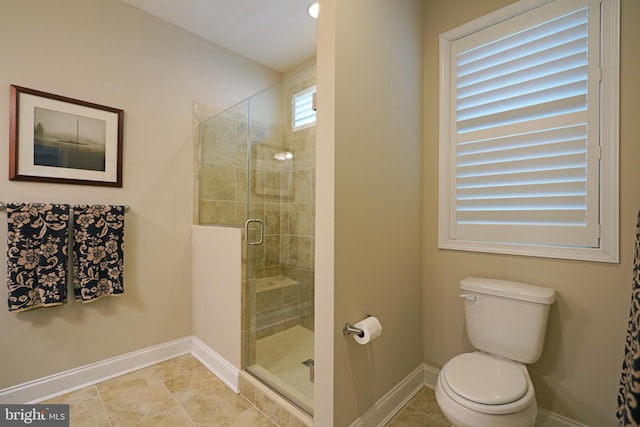 bathroom with a stall shower, baseboards, toilet, and tile patterned floors