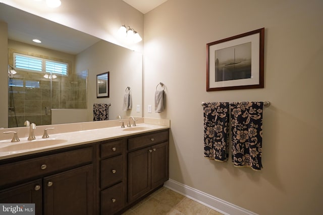 full bathroom featuring double vanity, baseboards, tile patterned floors, a shower stall, and a sink