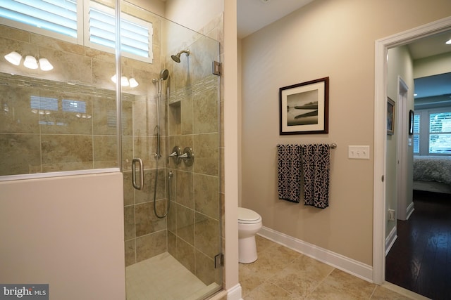 ensuite bathroom featuring a stall shower, ensuite bath, toilet, and baseboards