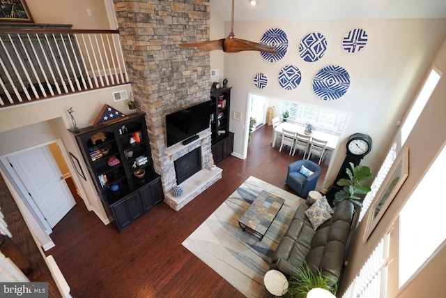 living room featuring a towering ceiling, dark wood-style floors, a fireplace, and visible vents