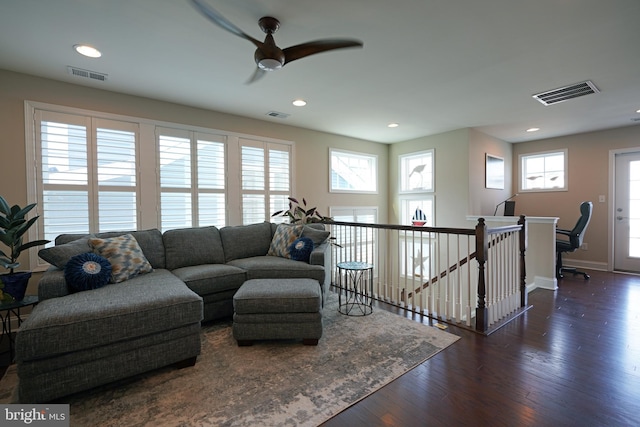 living area with dark wood-type flooring, visible vents, and baseboards