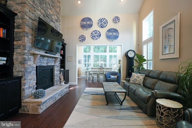 living area featuring high vaulted ceiling, a fireplace, baseboards, and wood finished floors