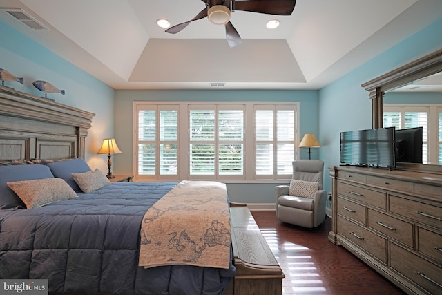 bedroom with ceiling fan, dark wood-style flooring, a raised ceiling, and visible vents