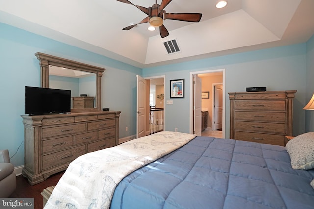 bedroom featuring ensuite bathroom, dark wood-style flooring, visible vents, baseboards, and a tray ceiling