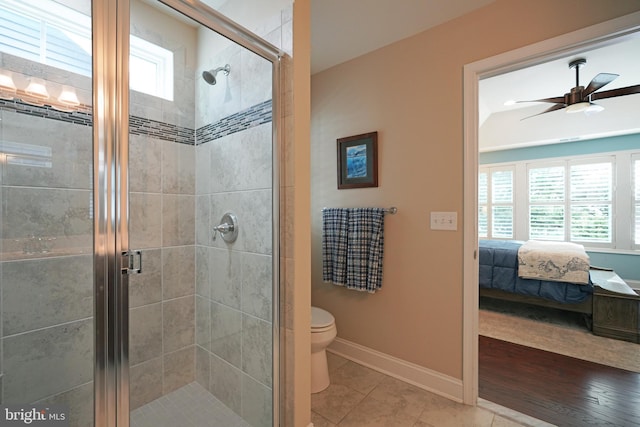 full bathroom featuring toilet, ceiling fan, a shower stall, ensuite bath, and baseboards