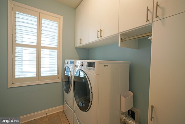 washroom featuring baseboards, cabinet space, and washing machine and clothes dryer