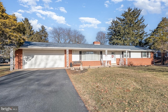 single story home with aphalt driveway, an attached garage, brick siding, a chimney, and a front yard