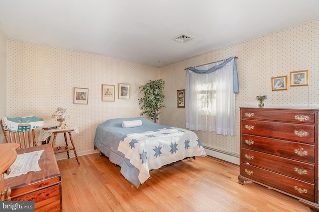 bedroom featuring a baseboard radiator, visible vents, baseboards, light wood finished floors, and wallpapered walls