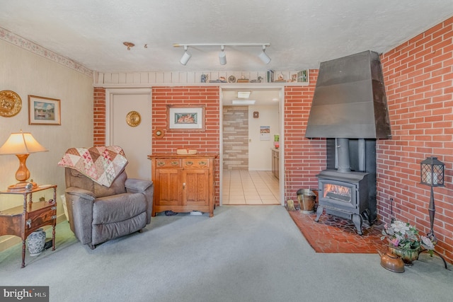 carpeted living area featuring a wood stove, brick wall, track lighting, and a textured ceiling