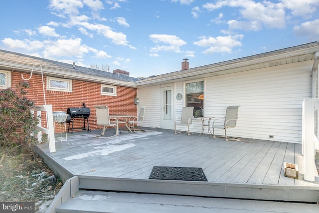 wooden deck with outdoor dining space and area for grilling